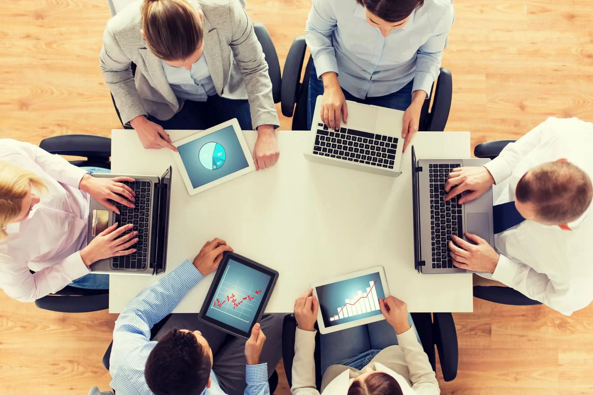 A team of people collaborating around a table with laptops